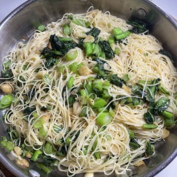 Steamed vegetable and noodle stir-fry in a stainless steel pan, promoting healthy eating and wholesome recipes.