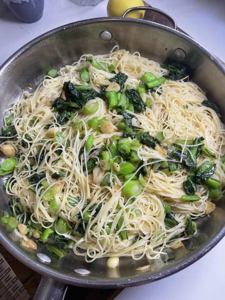 Steamed vegetable and noodle stir-fry in a stainless steel pan, promoting healthy eating and wholesome recipes.