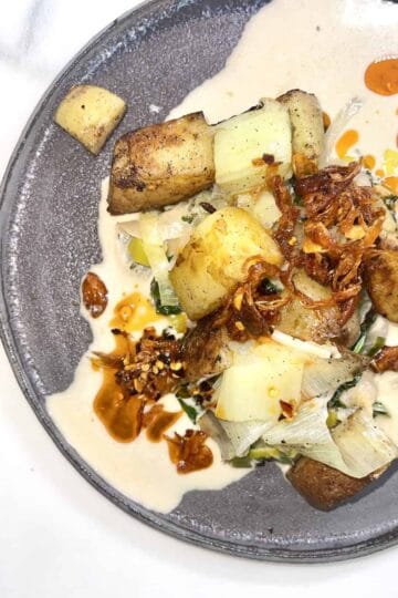 Potato and leek dish with coconut miso sauce and crispy toppings.