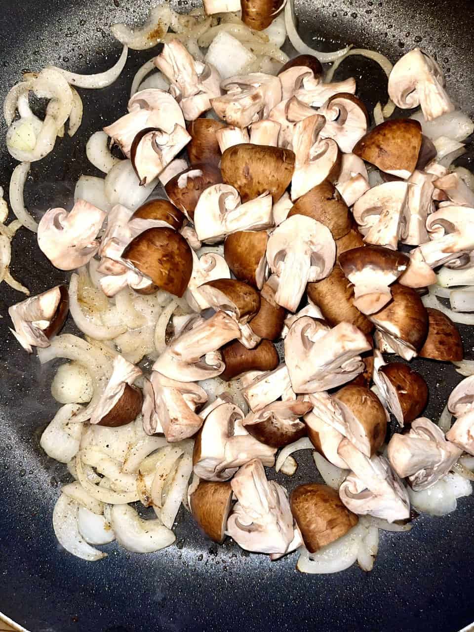 Sauteed mushrooms and onions cooking in a skillet. Fresh, healthy ingredients ideal for vegetarian meals.