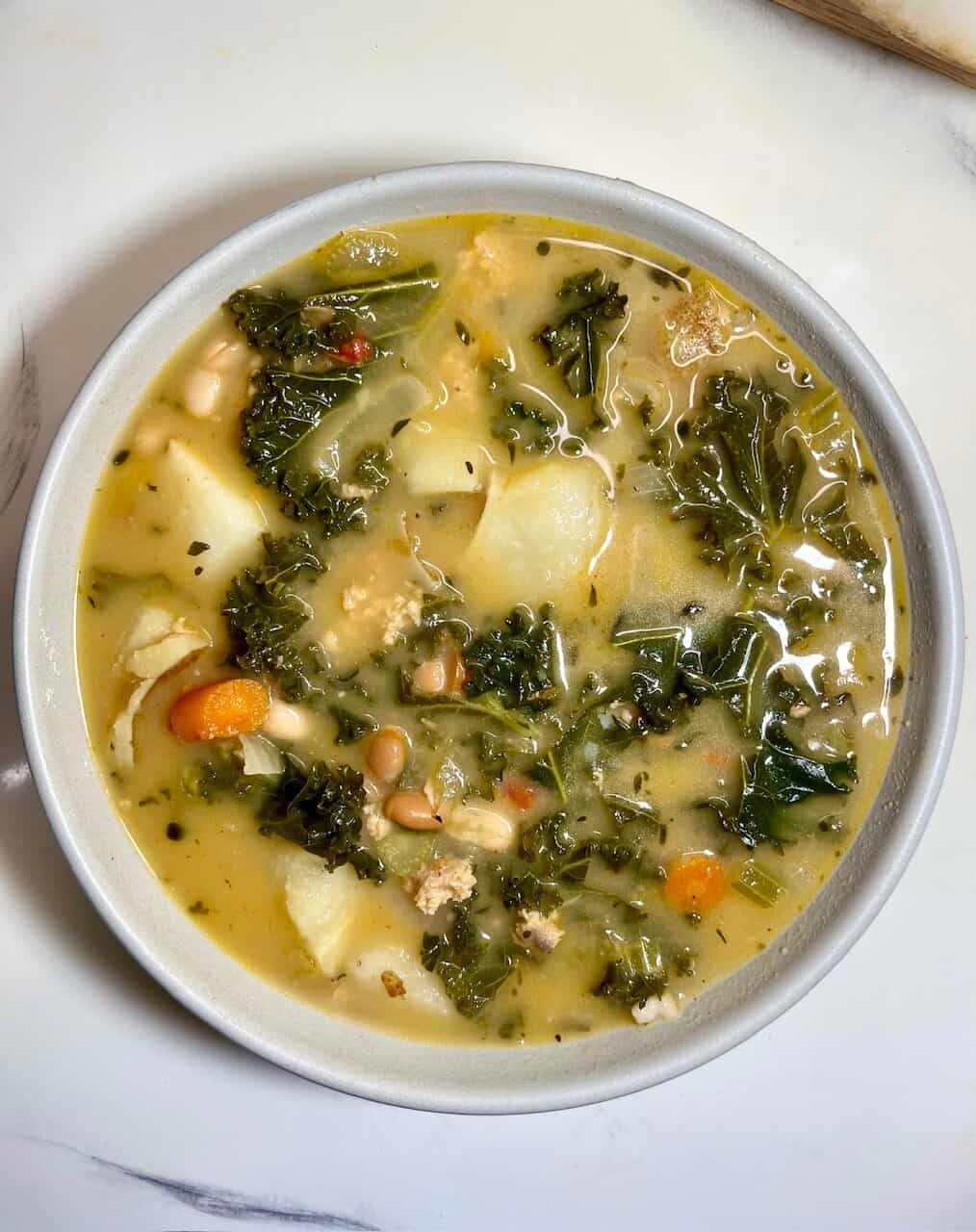 Comforting vegetable soup with kale, potatoes, carrots, and herbs for nourishing wellness.