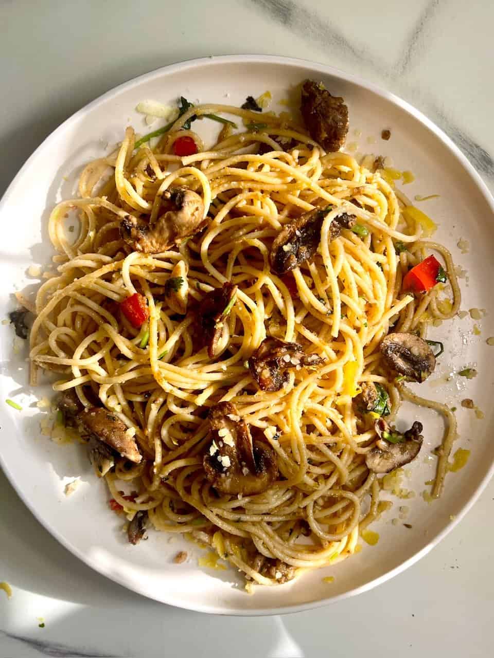 Sweet potato or mushroom pasta with red bell peppers on a white plate, healthy vegetarian meal.