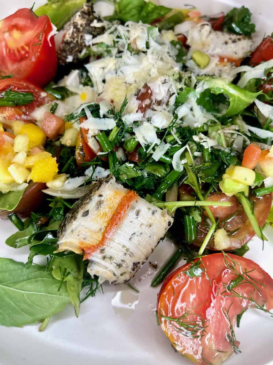 Fresh healthy garden salad with tomatoes, greens, cheese, and fish for clean eating and wellness.