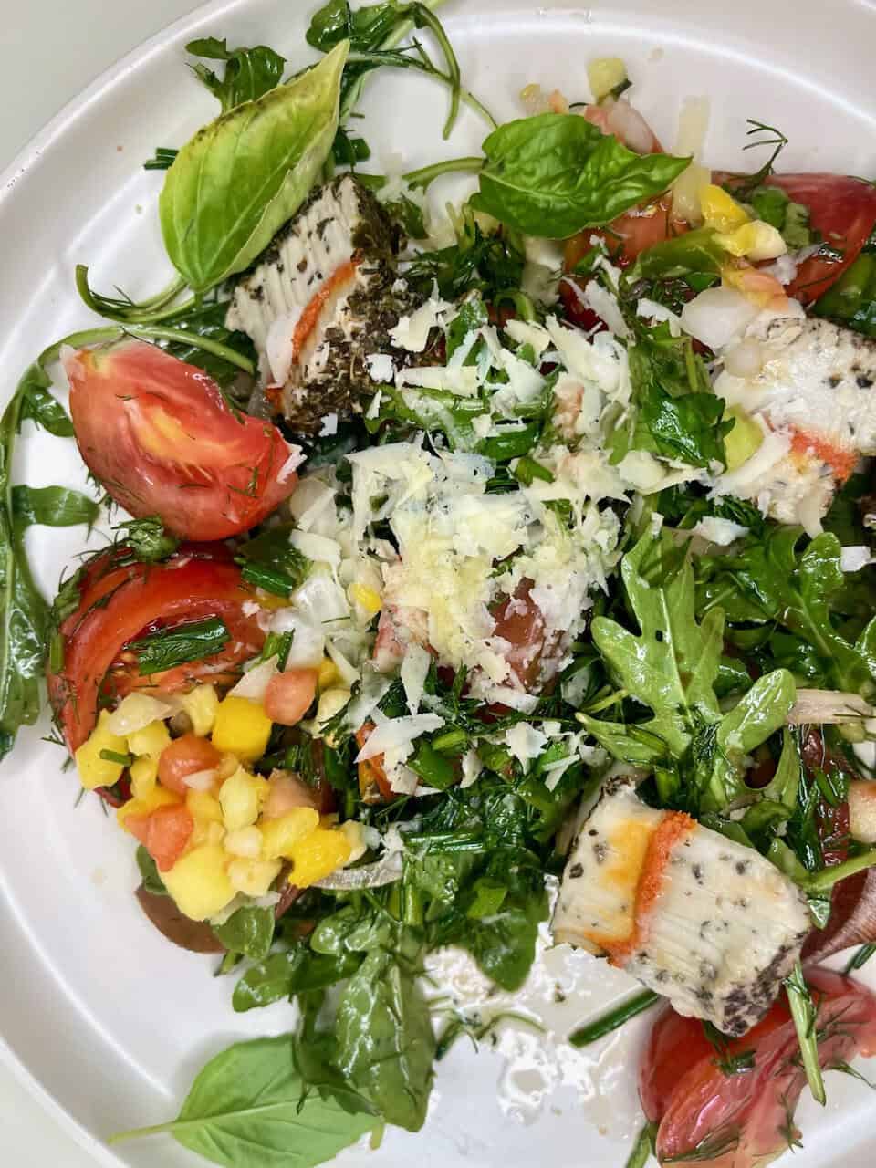 Fresh vegetarian salad with herbs, tomatoes, cheese, and mixed greens, perfect for a healthy, wholesome meal.