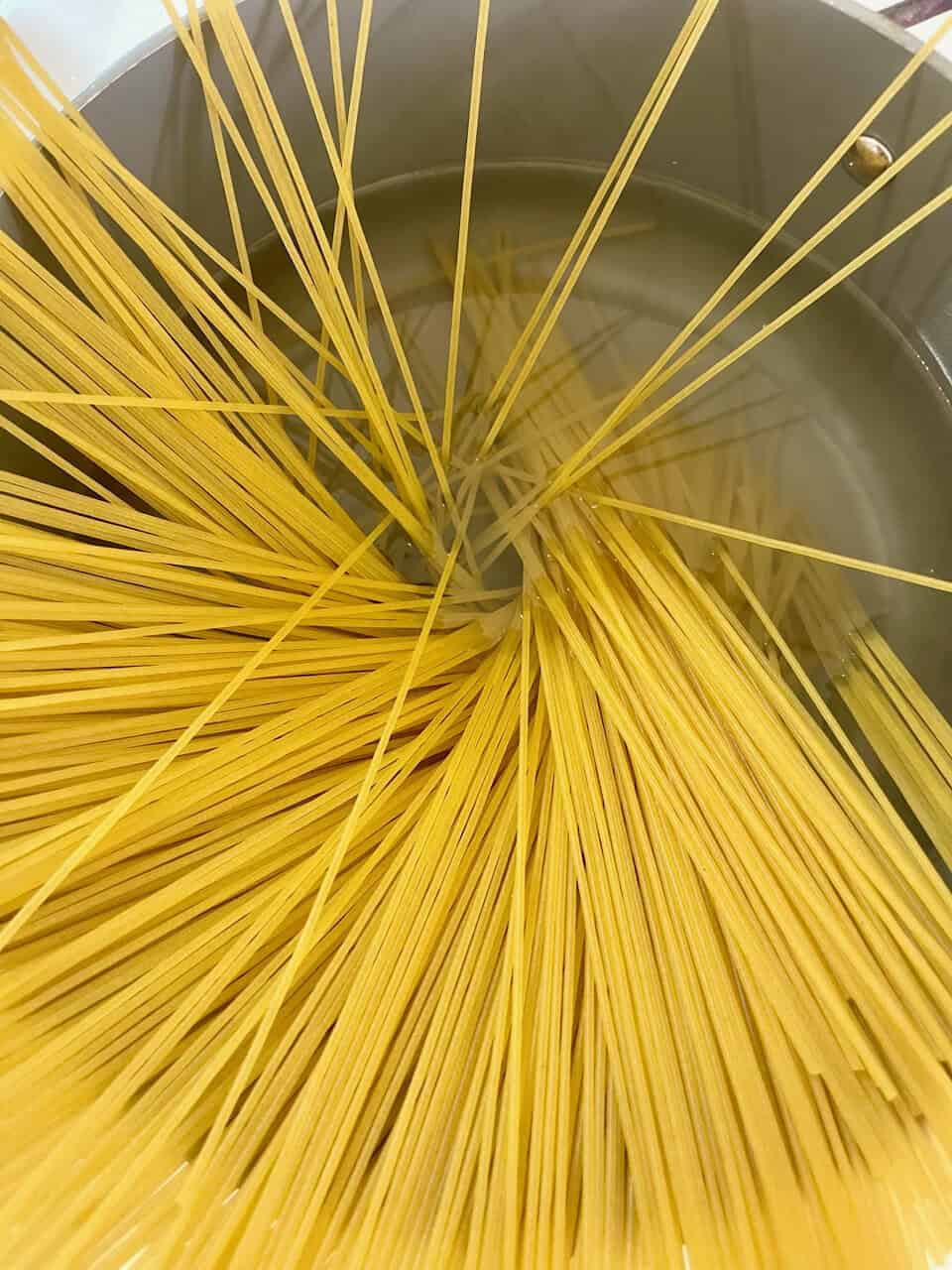 Raw spaghetti pasta boiling in water for healthy cooking and nourishing your body with nourishing ingredients.
