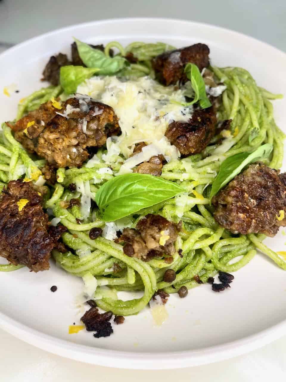 Fresh zucchini noodles with lentil meatballs, basil, and cheese, healthy plant-based vegan meal.