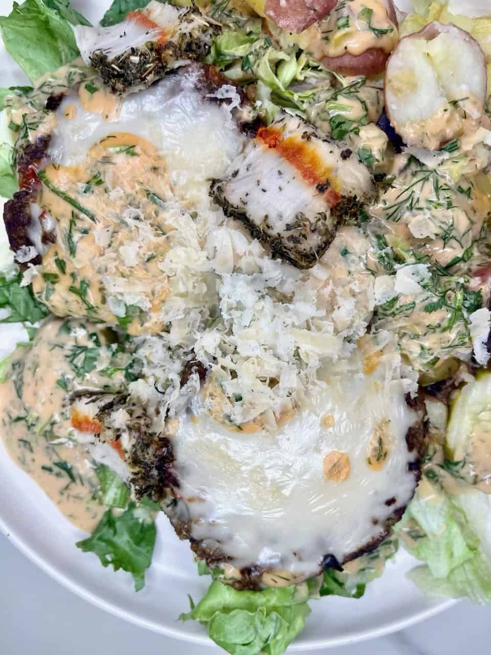 Sunny side up eggs with smoked salmon on a bed of greens and herbs, topped with creamy dressing and shredded cheese.