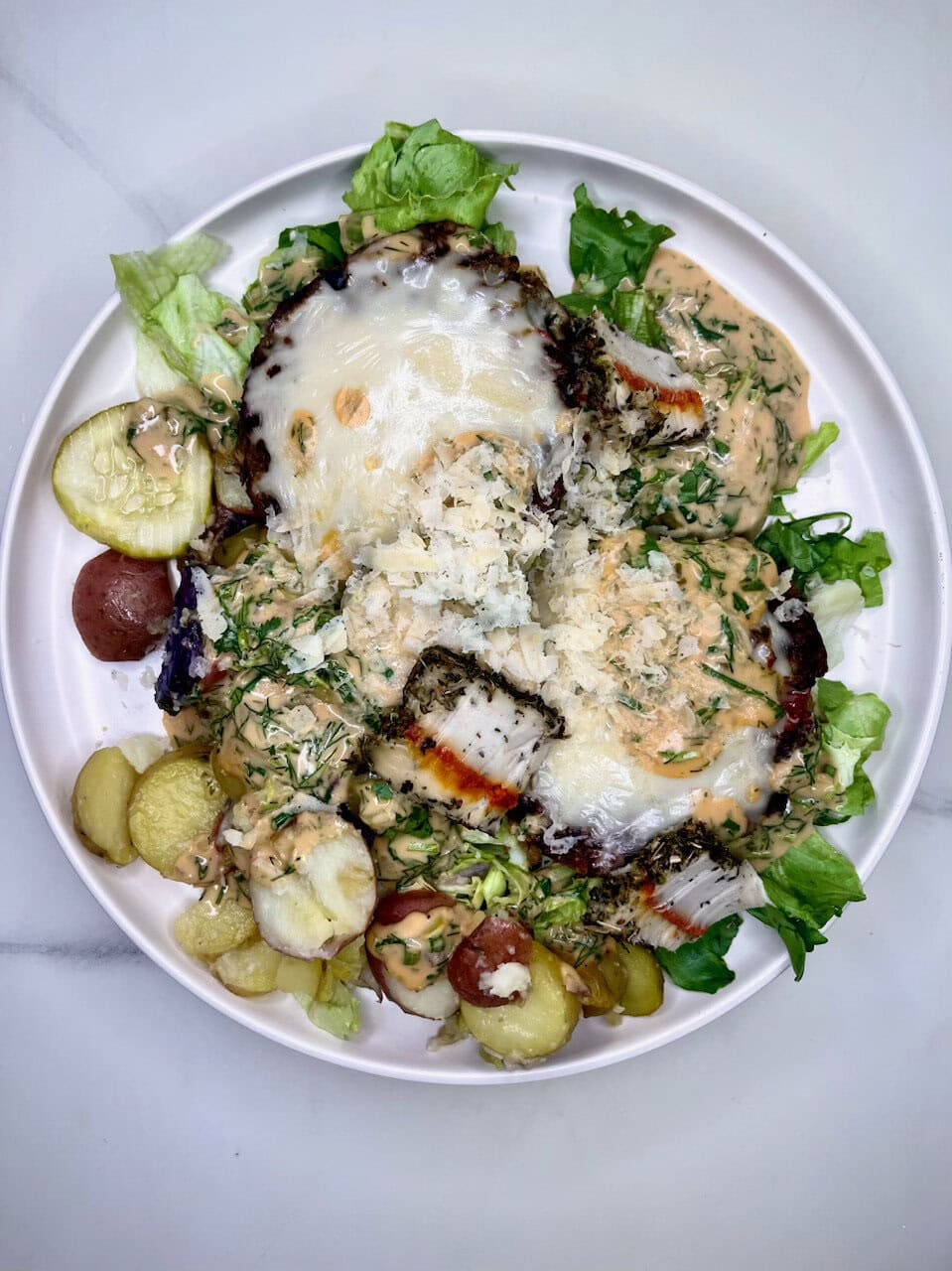 Fresh salad with grilled fish, leafy greens, potatoes, and creamy dressing, promoting healthy eating and wellness.