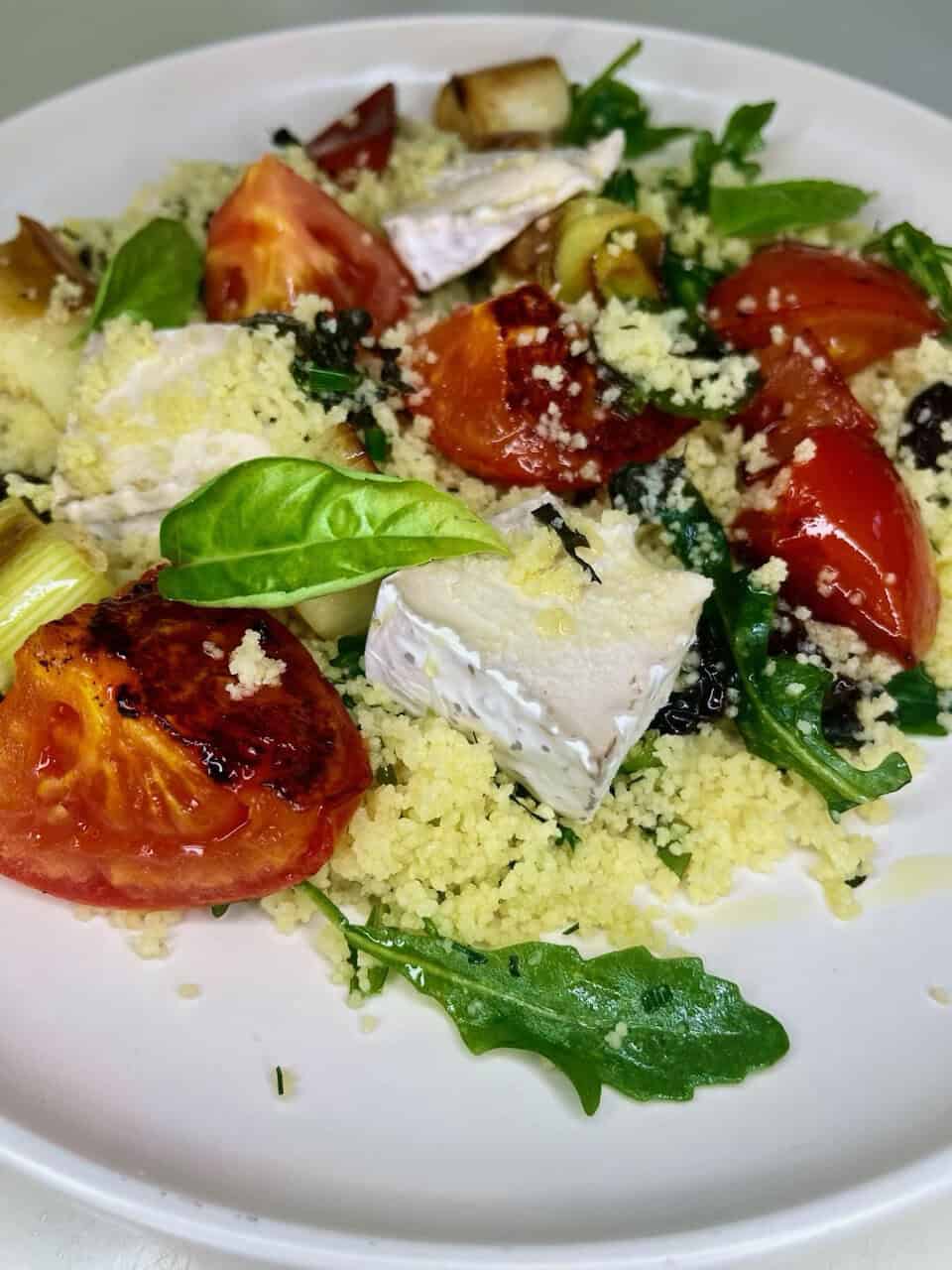 Fresh vegetarian salad with tomatoes, feta cheese, quinoa, basil, spinach, and roasted eggplant.