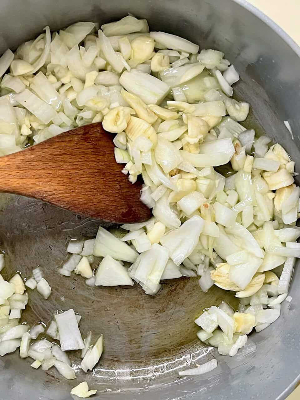 Sautéed onions and garlic in a stainless steel pan for healthy cooking and flavor enhancement.