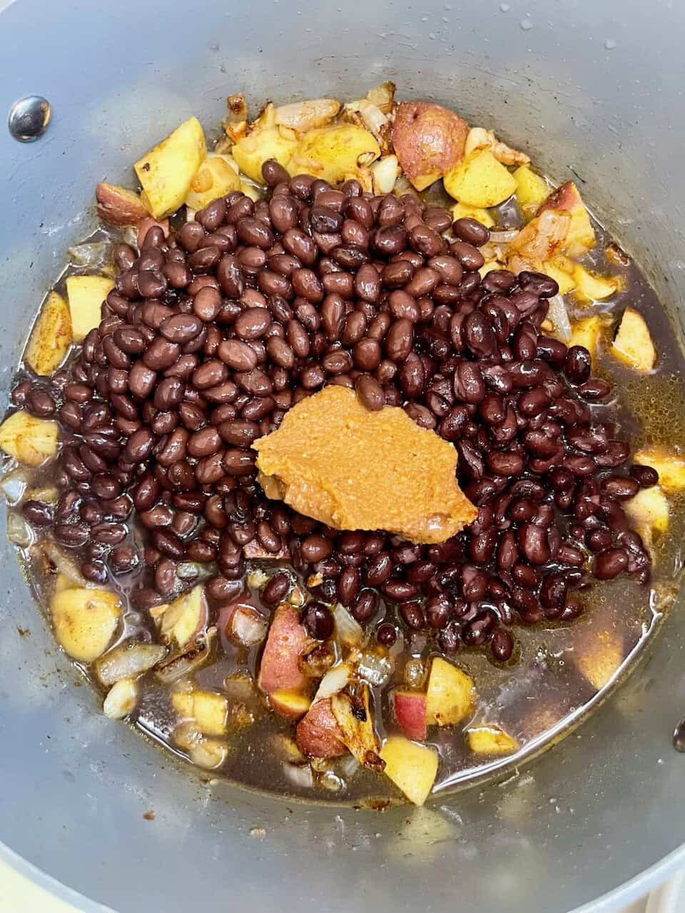 Black beans cooking with sweet potatoes and seasonings for healthy meal prep.