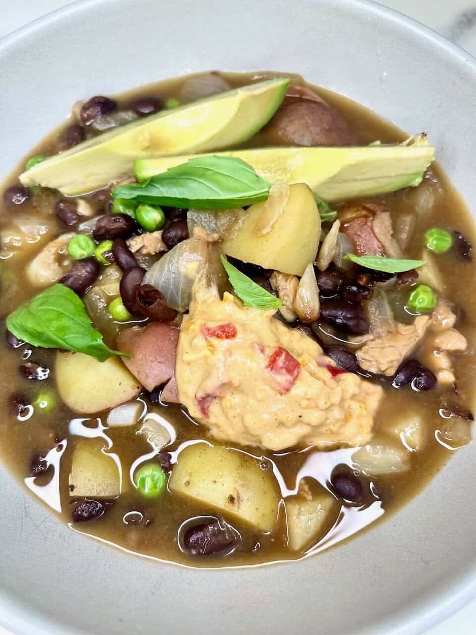 Creamy chicken and black bean soup with fresh avocado and herbs, a nourishing healthy meal for wellness and vitality.