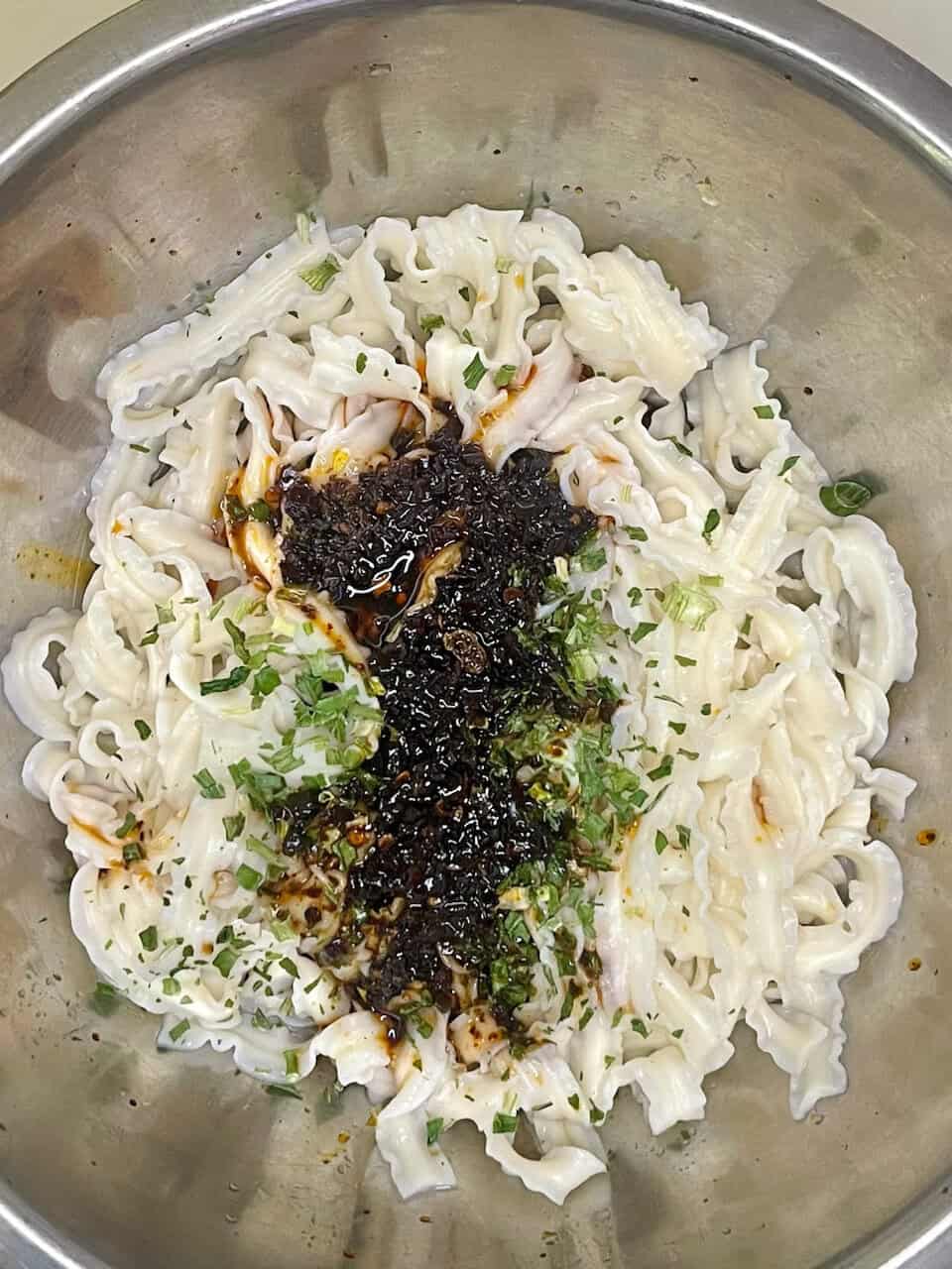 Silky handmade noodles with savory soy sauce and chopped green onions in a stainless steel bowl.