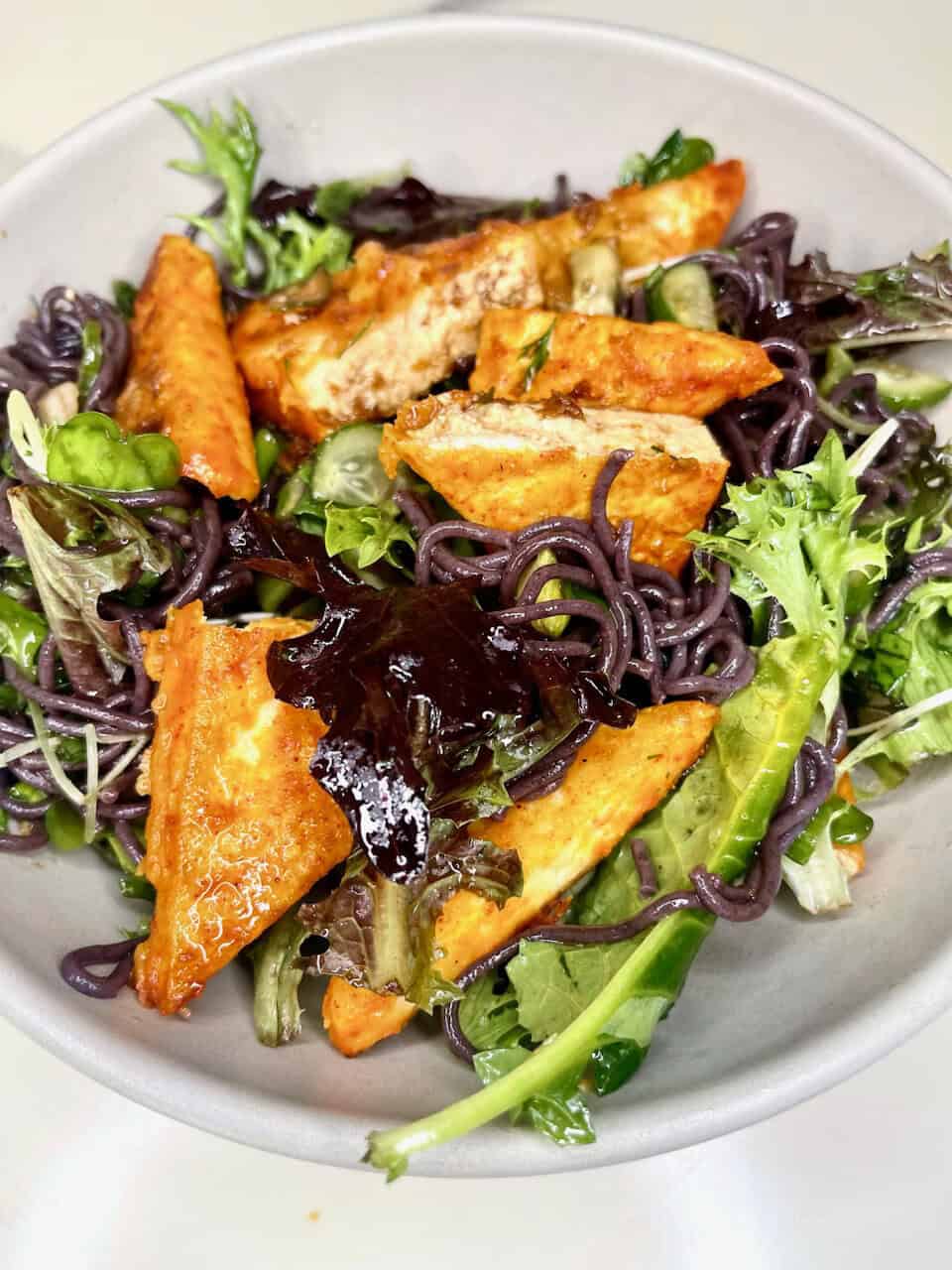 Grilled tofu and mixed greens salad with black bean pasta, fresh vegetables, and light dressing.