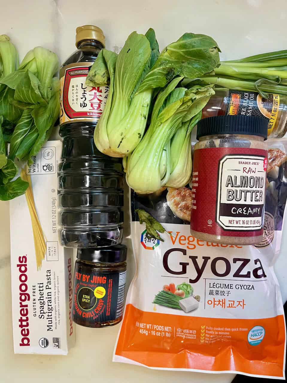 Fresh vegetables, soy sauce, almond butter, and noodles for nutritious plant-based meals.