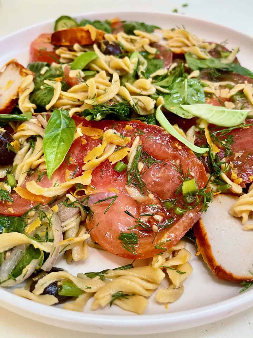 Fresh vegetarian pasta salad with tomatoes, basil, and mixed greens, healthy and flavorful vegetarian meal.