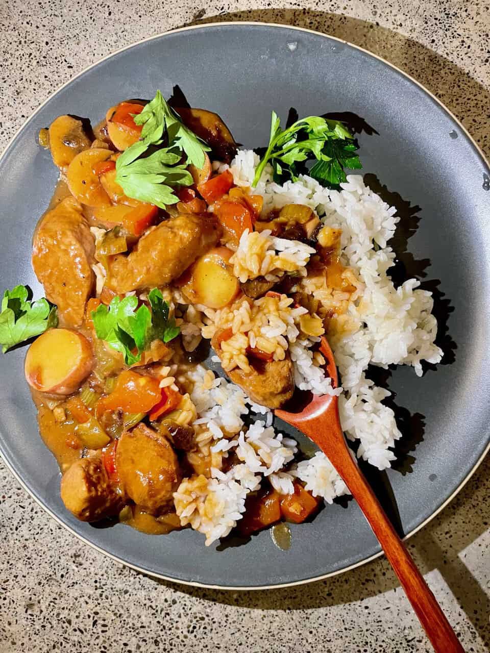 Savory chicken vegetable stew with rice on a gray ceramic plate.