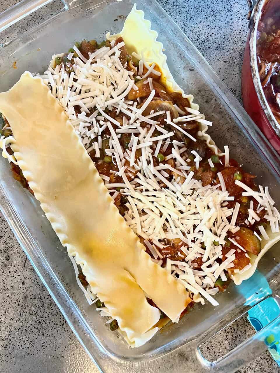 Cheesy vegetable lasagna casserole in a clear glass dish, baked with cheese and pasta ribbons.