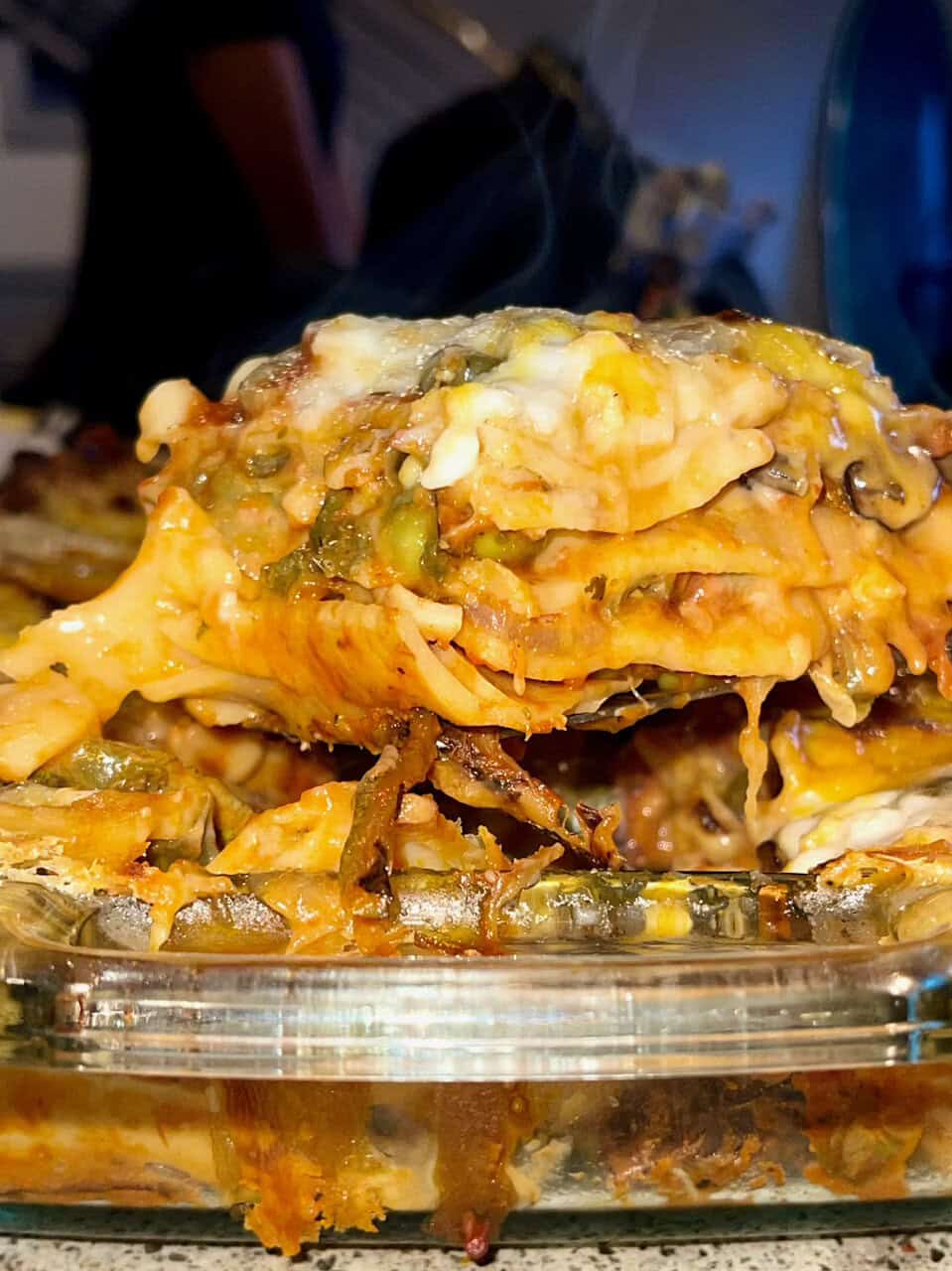 Cheesy baked casserole dish with vegetables and melted cheese in a glass baking dish.