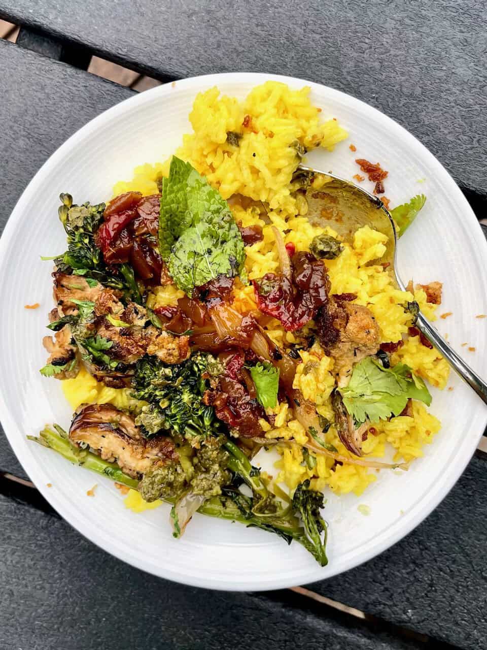 Steamed yellow rice with vegetables, herbs, and flavorful sauce on a white plate for healthy eating.