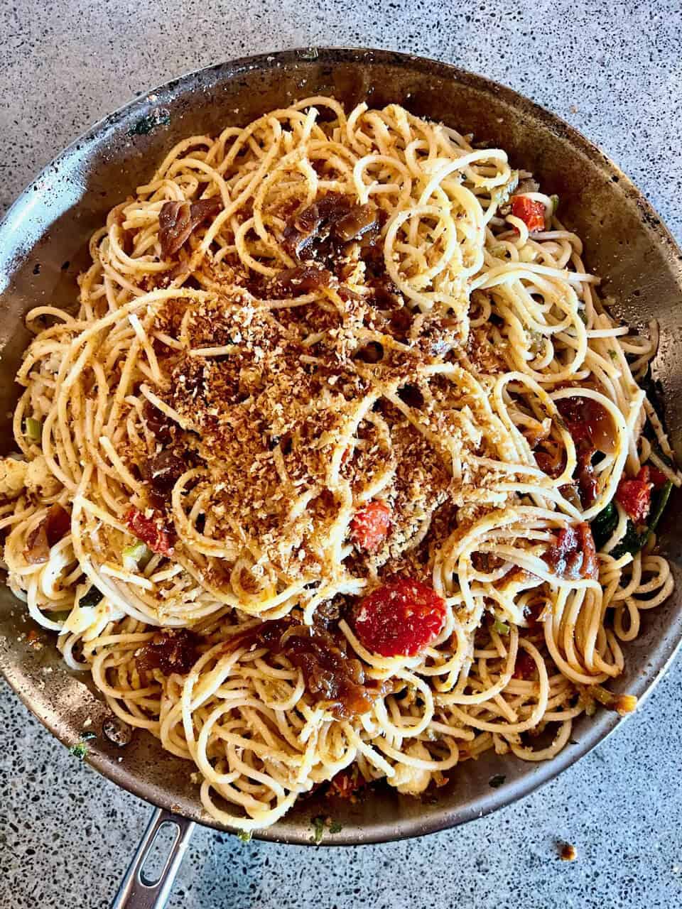 Creamy mushroom pasta with cherry tomatoes and grated cheese in a skillet, homemade healthy vegetarian recipe.