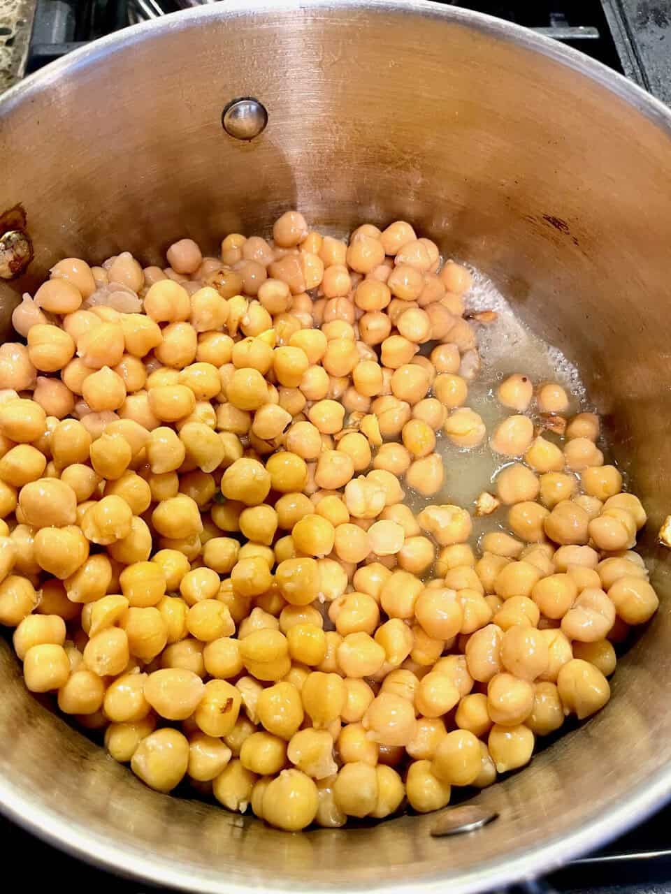 Chickpeas cooking in a stainless steel pot for healthy plant-based meal.