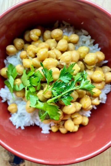 Cooked chickpeas served over rice with fresh parsley garnish for a healthy, protein-rich meal.