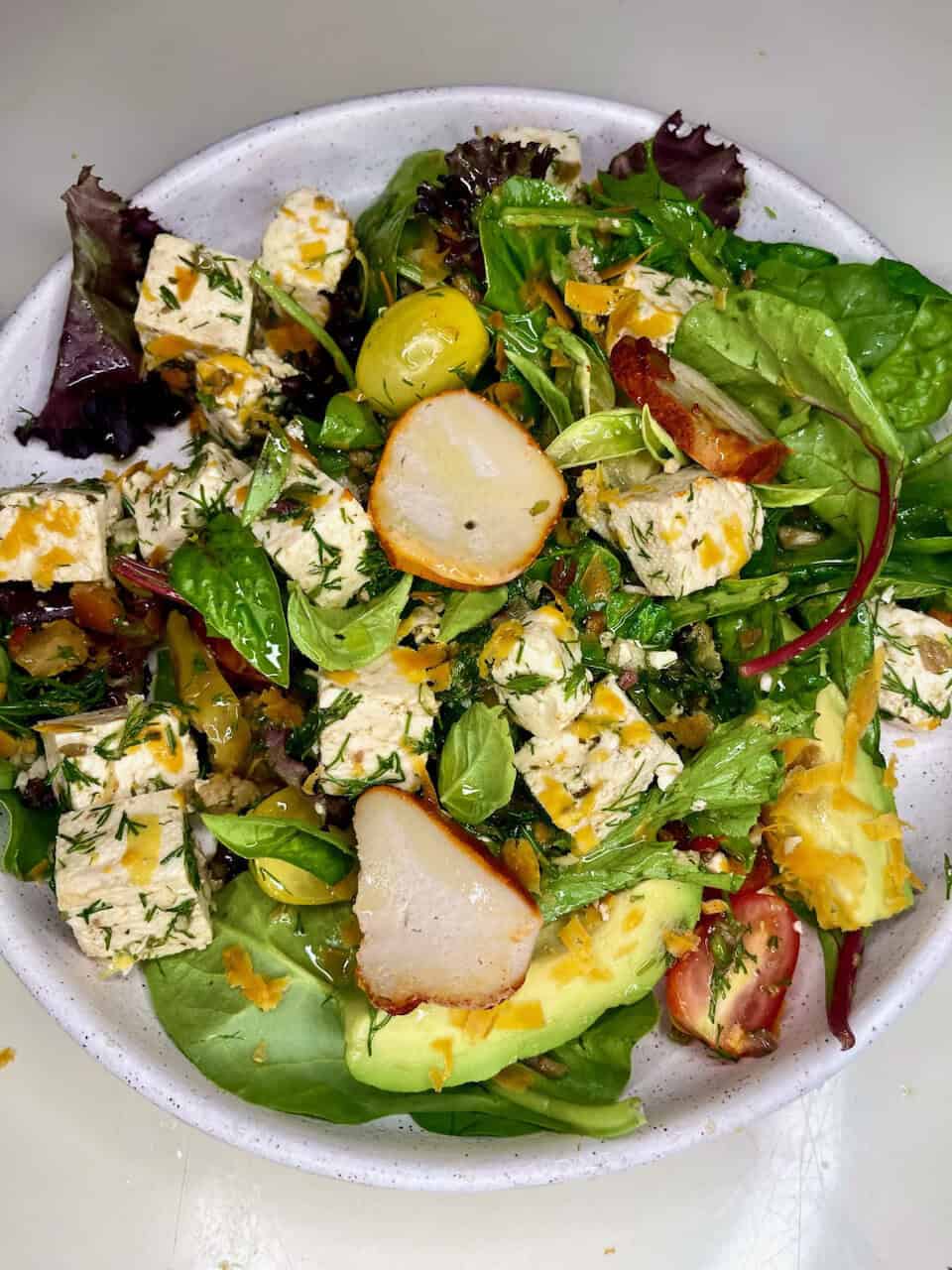 Fresh healthy green salad with tofu, avocado, and tomatoes, emphasizing clean eating and wellness.