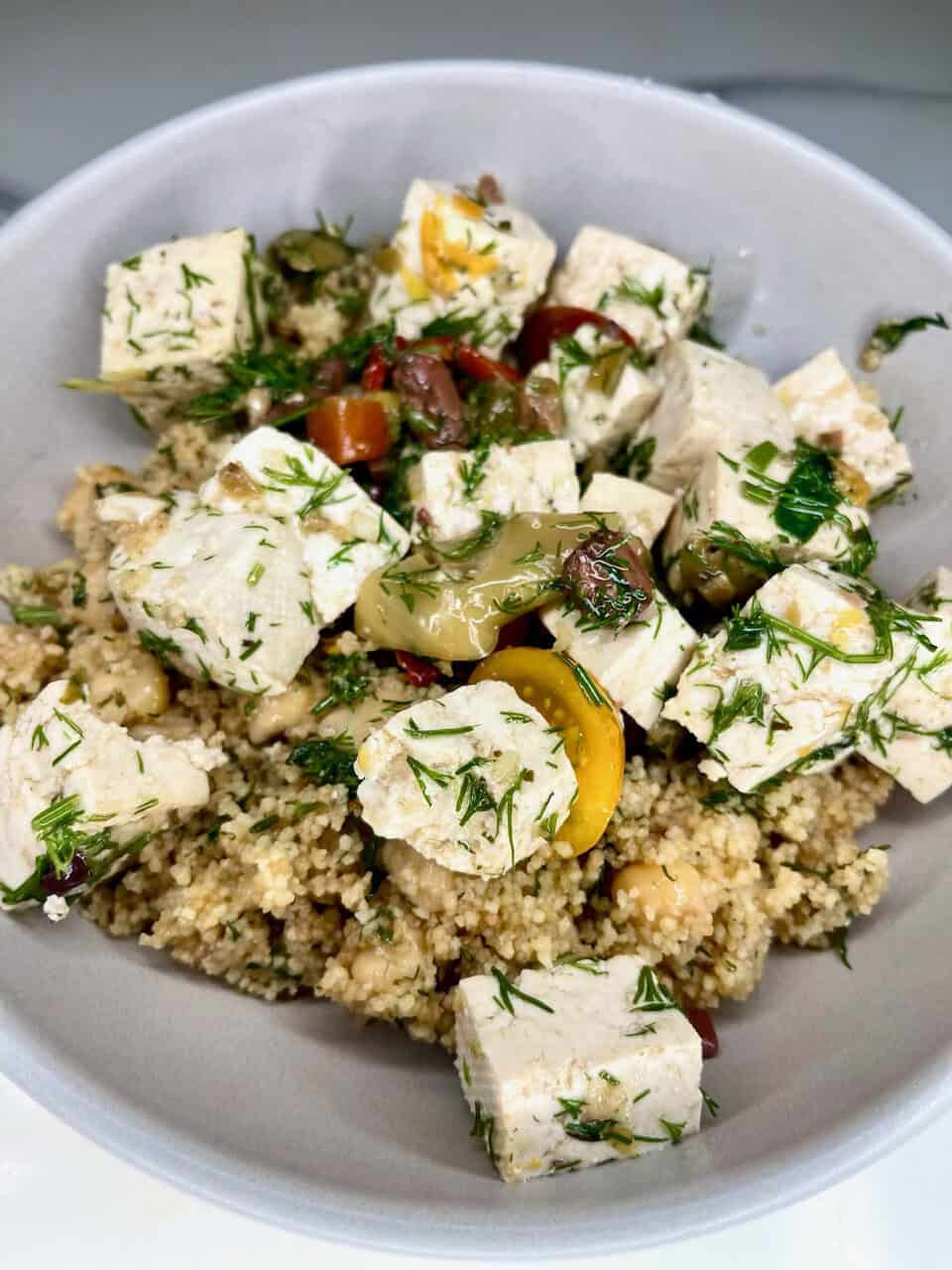 Fresh vegan feta cheese salad with herbs served over quinoa for a healthy, plant-based meal.