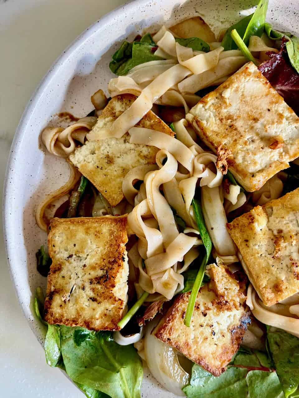 Pad thai rice noodles with golden pan-fried tofu, greens and tomatoes