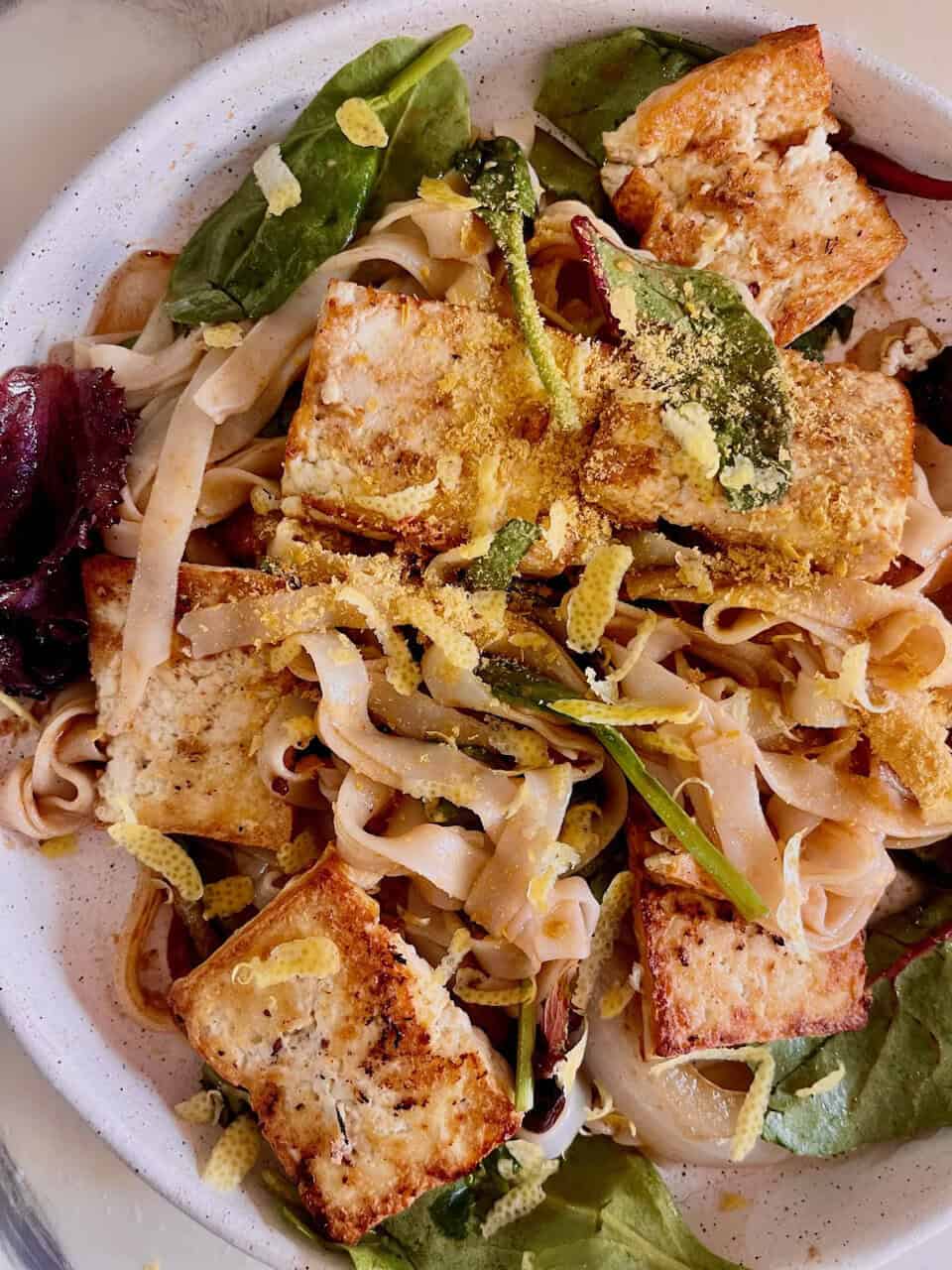 Tofu and vegetable noodle salad with mixed greens and fresh herbs, highlighting vegan, healthy, and plant-based ingredients for SEO.