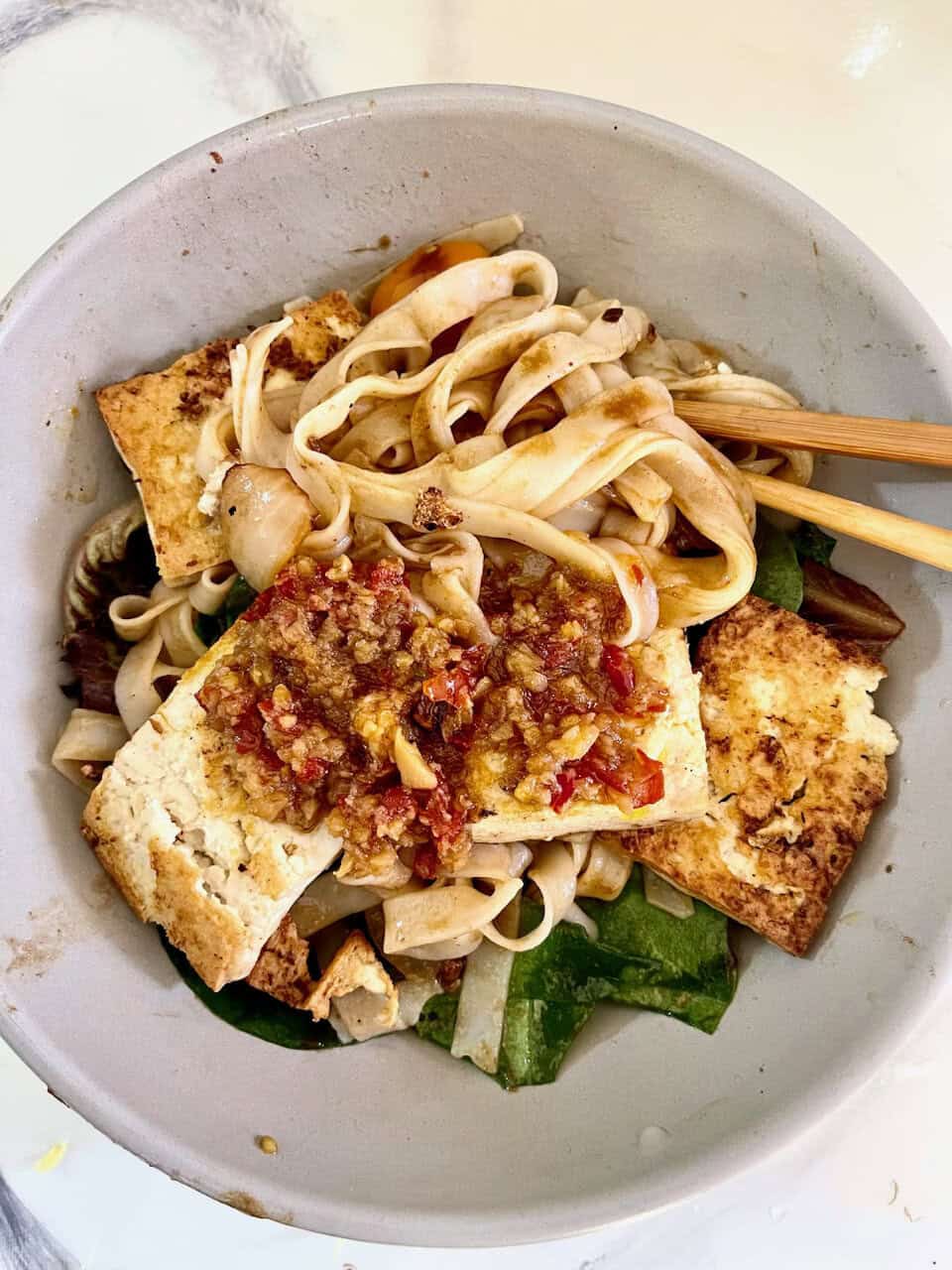 Vegetarian tofu noodle bowl with fresh vegetables and savory sauce.