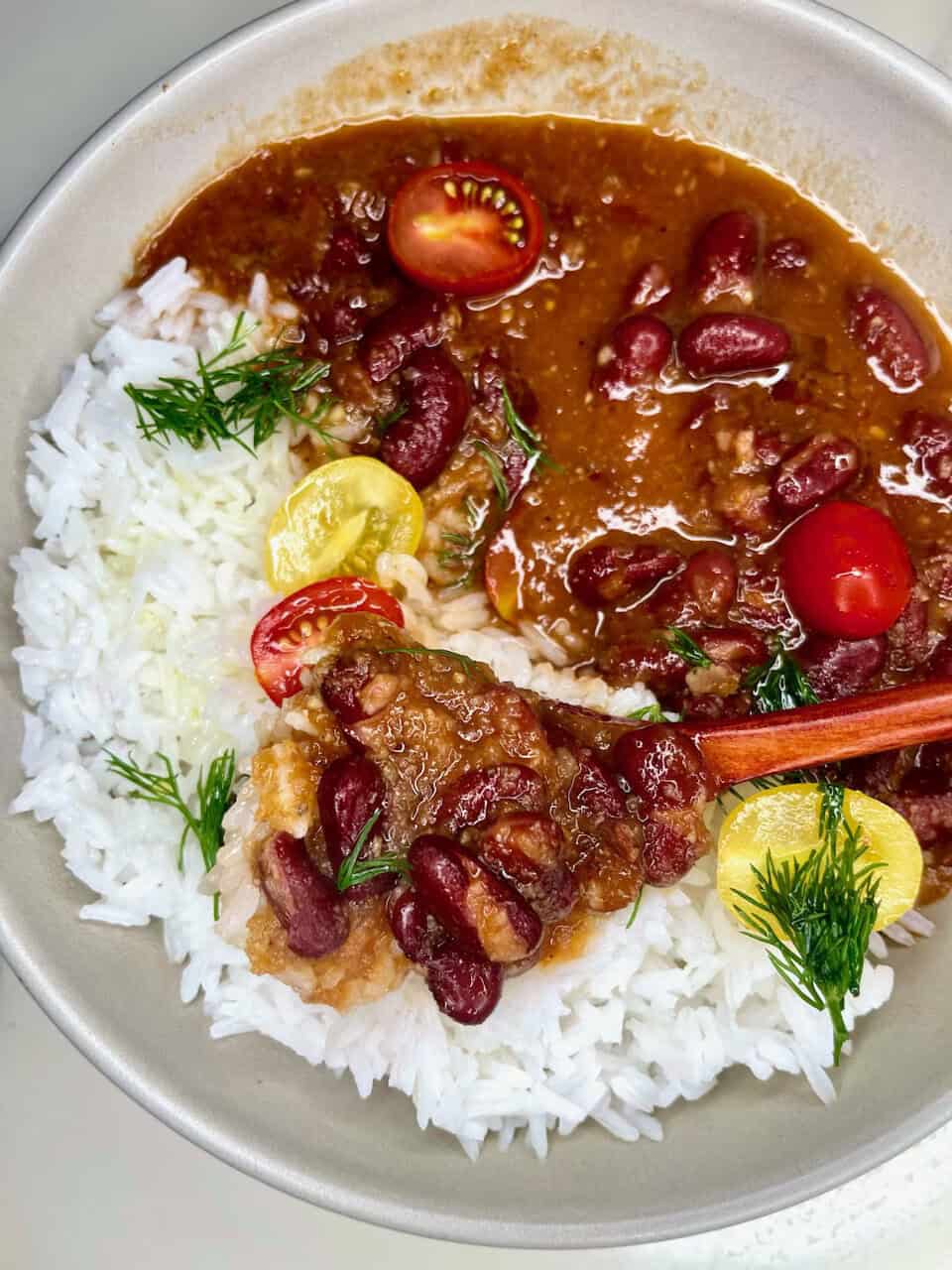 Rich kidney bean stew served over fluffy white rice with cherry tomatoes and fresh herbs. Perfect comfort food for a healthy meal.