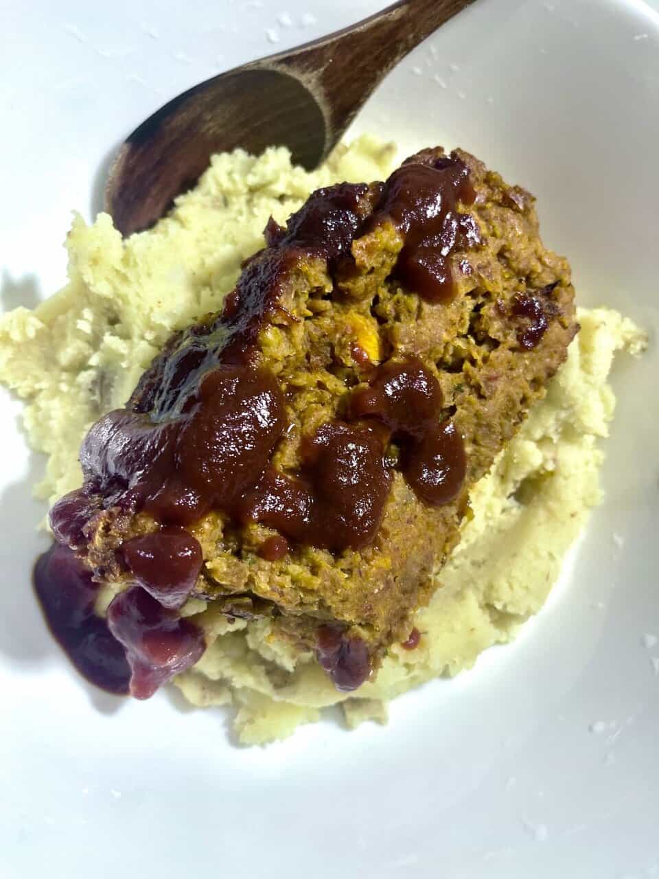 Homemade meatloaf with mashed potatoes and gravy served on a white plate.