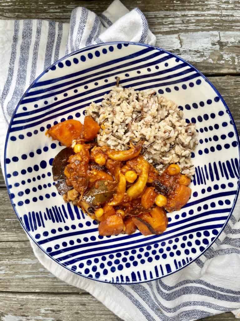 Savory vegetable stew with rice and beans on decorative blue and white plate.