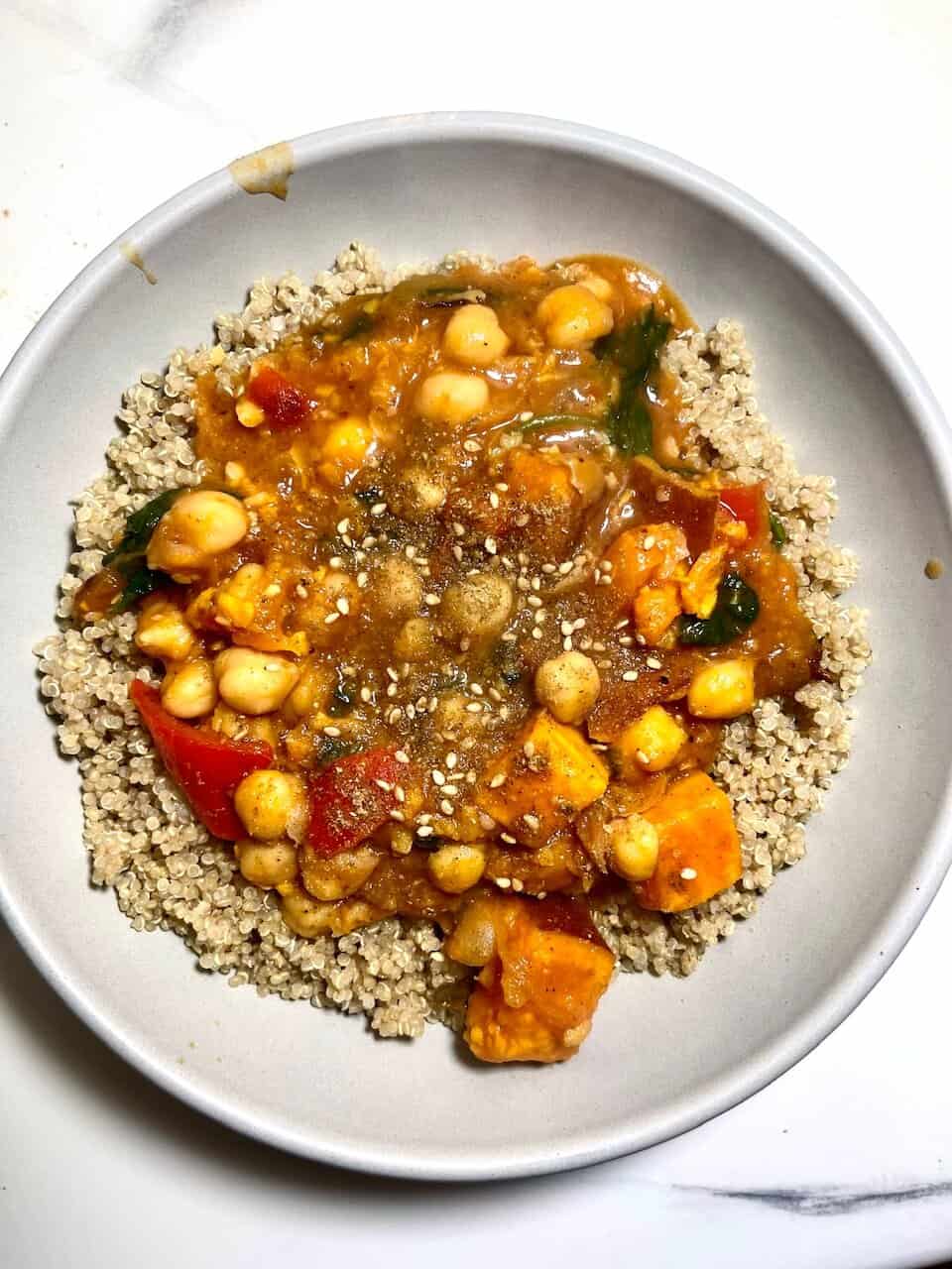 Steamed quinoa topped with hearty vegetable curry, healthy and gluten-free plant-based meal.