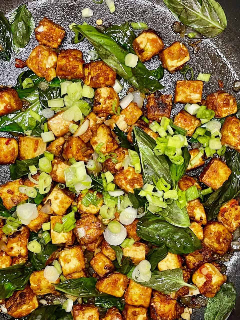 Crispy tofu with fresh green onions and basil leaves, cooked in a flavorful pan sauce, healthy vegetarian recipe.