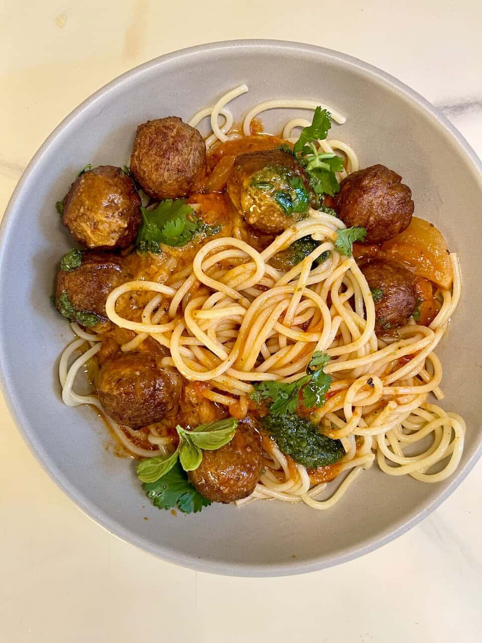 Savory spaghetti with meatballs and herbs on a white bowl, healthy eats.