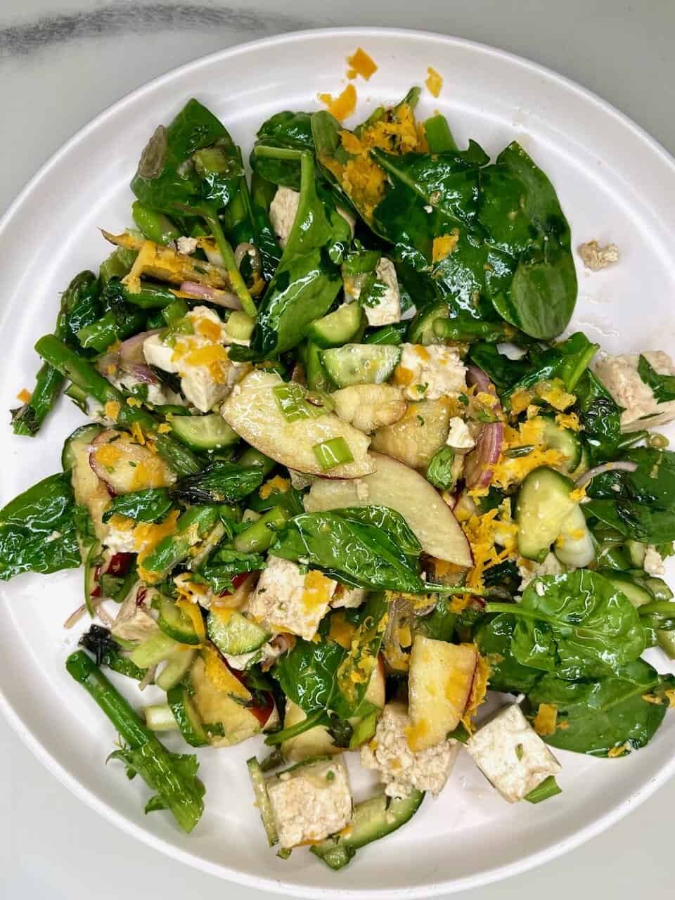 Fresh green vegetable salad with tofu, apples, and citrus zest, promoting healthy eating and wellness.