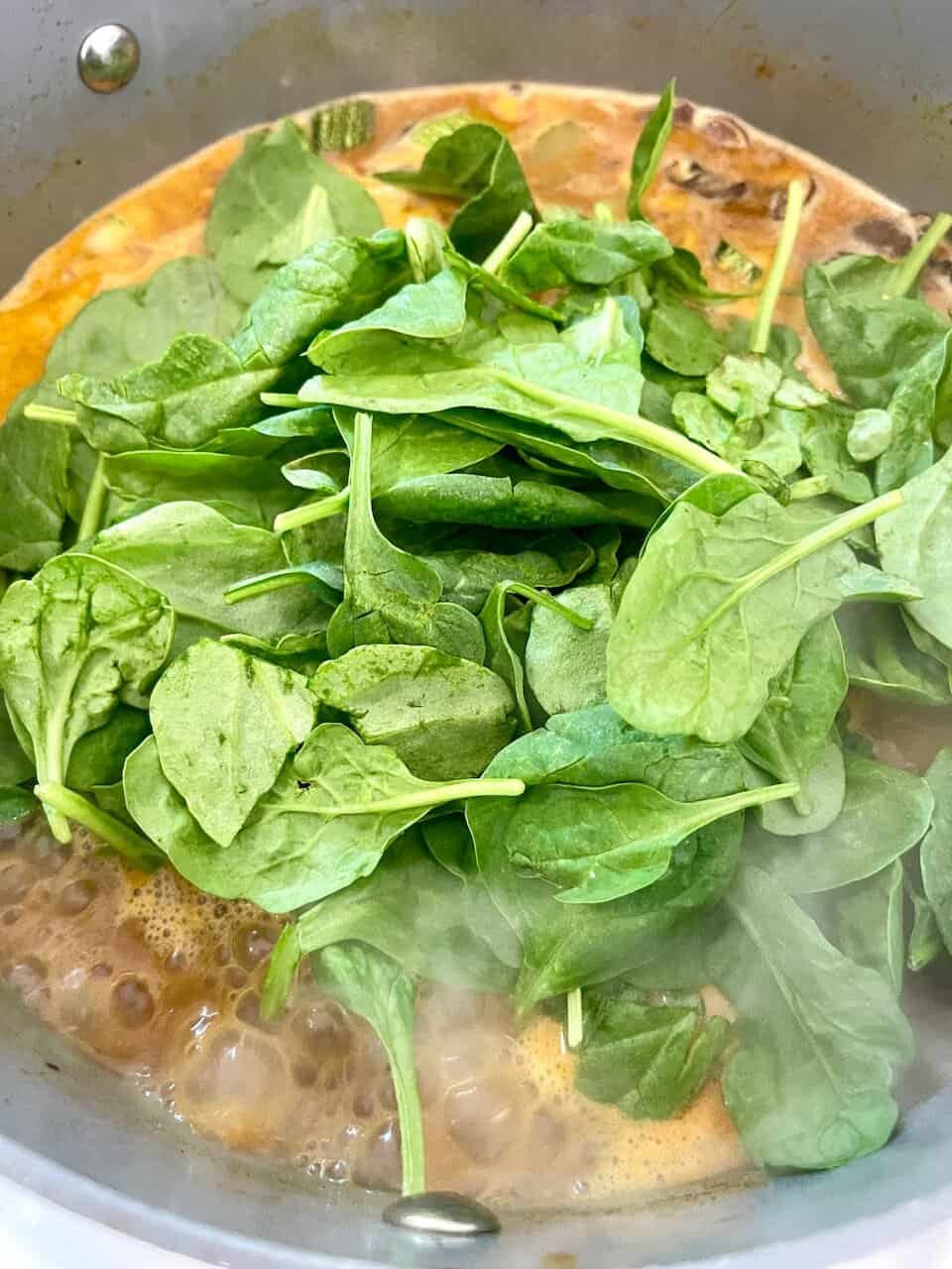 Fresh spinach added to a cooking dish, promoting health and wholesome eating.