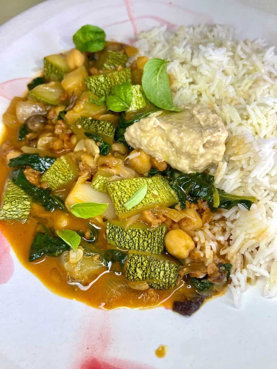 Fresh vegetable curry with rice and creamy hummus, highlighting healthy plant-based meal options.