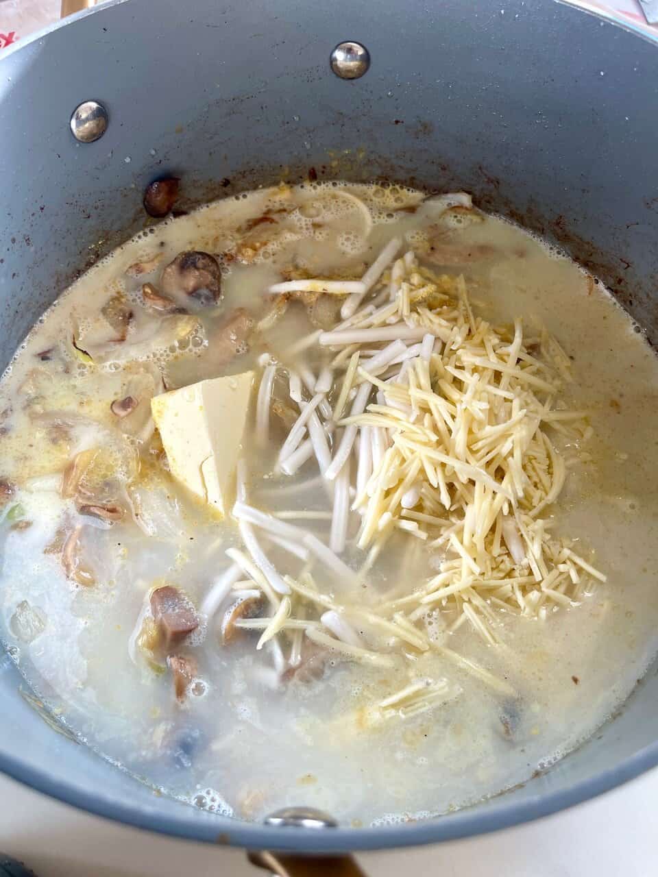 Creamy mushroom and cheese soup cooking in a pot, perfect for comforting homemade meals.