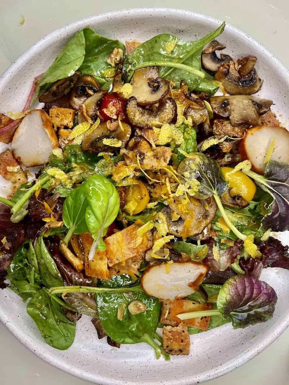 Fresh vegetable salad with mixed greens, mushrooms, cherry tomatoes, and crispy bread croutons. Healthy, delicious plant-based meal.
