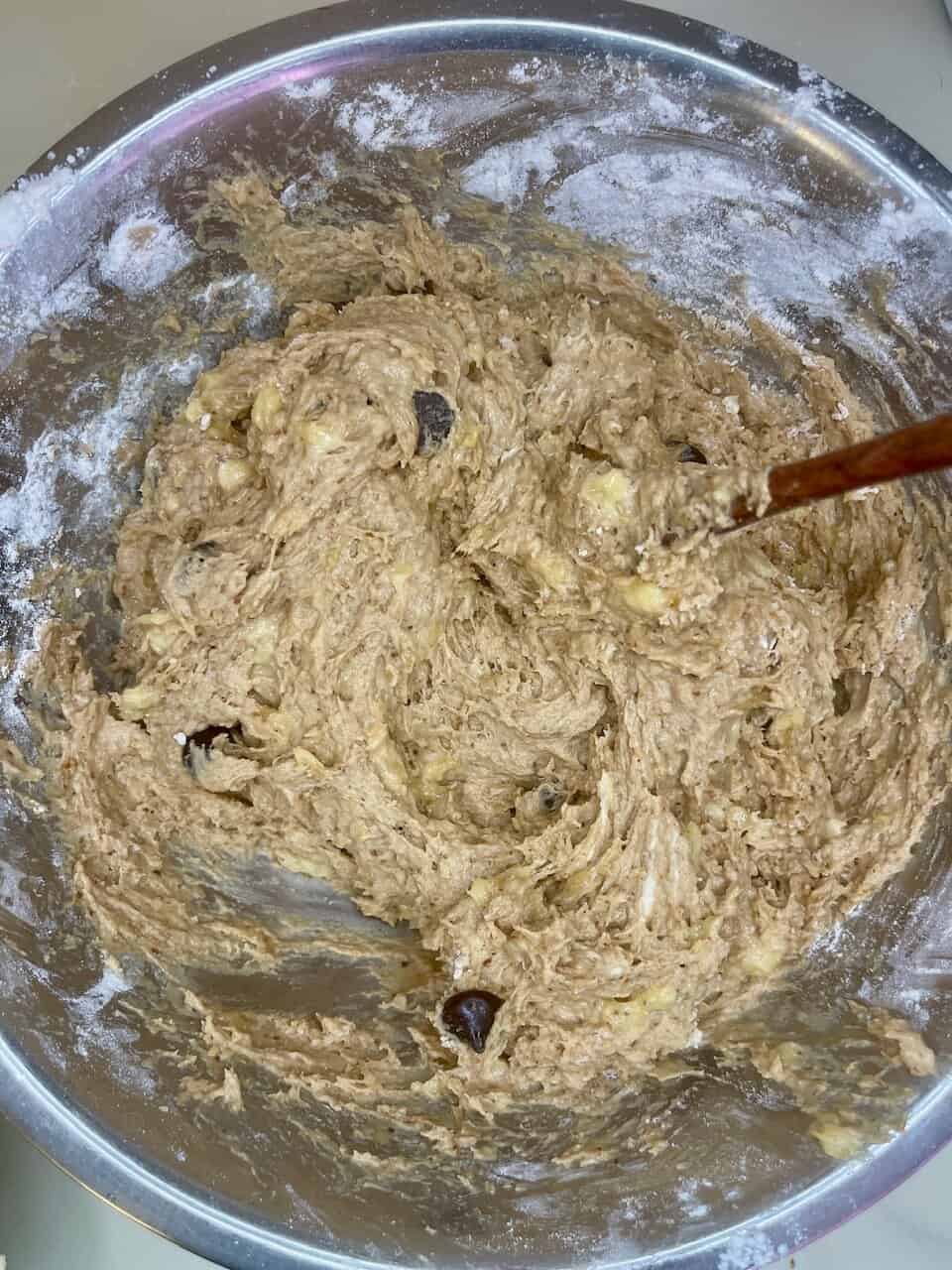 Creamy cookie dough mixture with chocolate chips in a stainless steel bowl, ready for baking or chilling.
