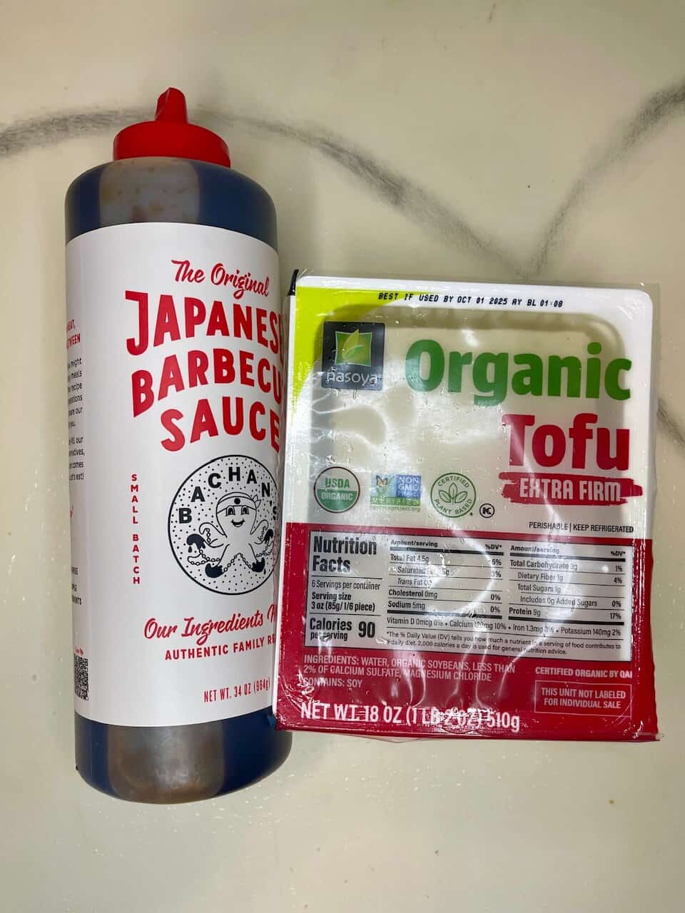 Japanese barbecue sauce and organic tofu packaging on a kitchen counter.