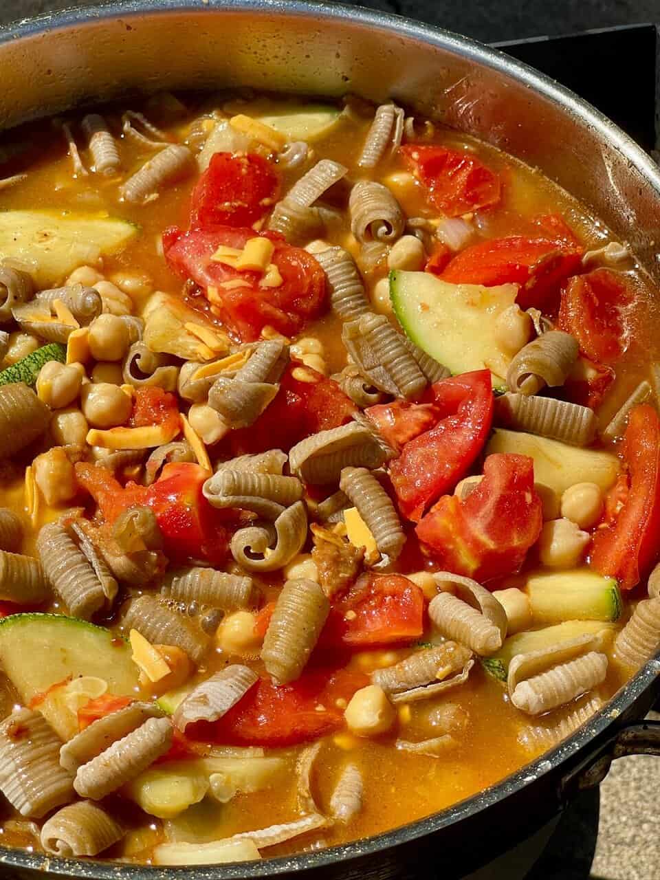 Savory vegetable pasta soup with chickpeas, zucchini, and tomatoes in a flavorful broth.