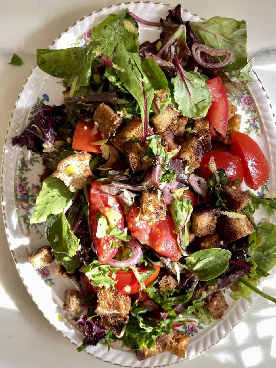 Fresh vegan salad with mixed greens, tomatoes, onions, and crispy croutons, healthy plant-based meal for a balanced diet.