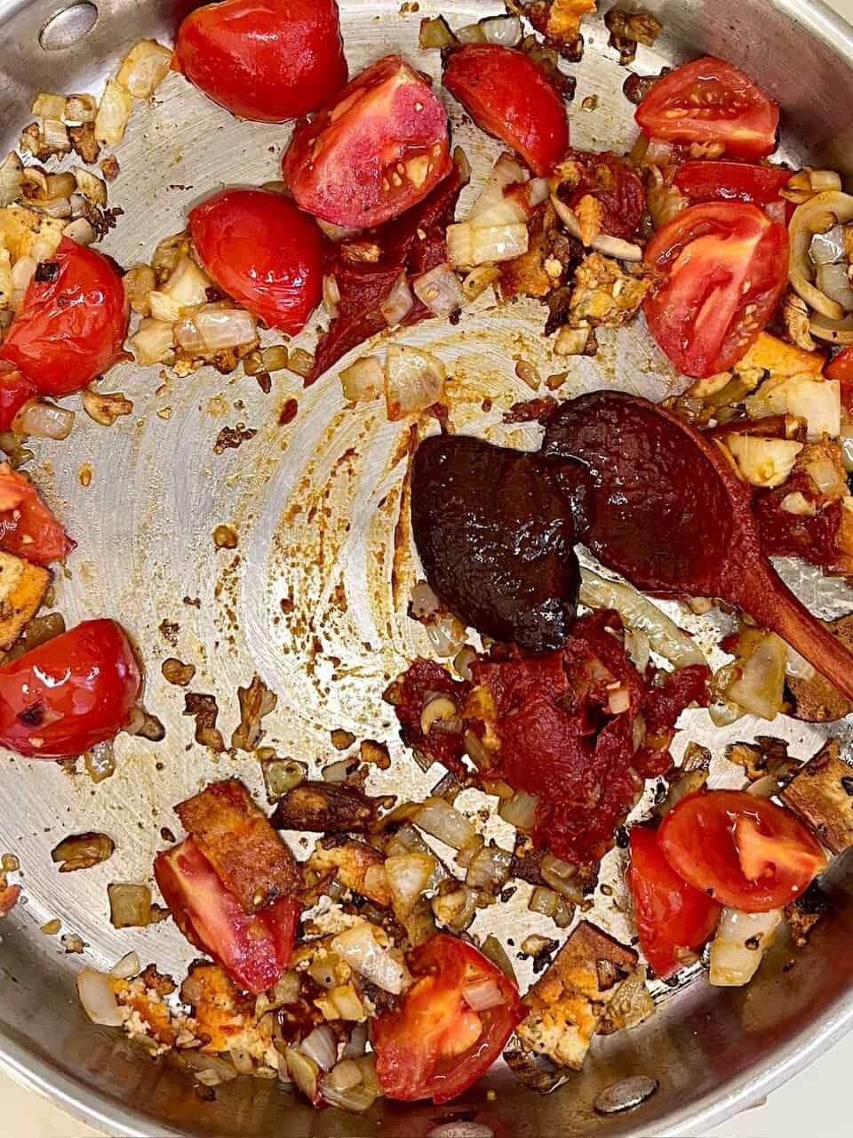 Heirloom tomatoes with caramelized onions and herbs in a skillet.