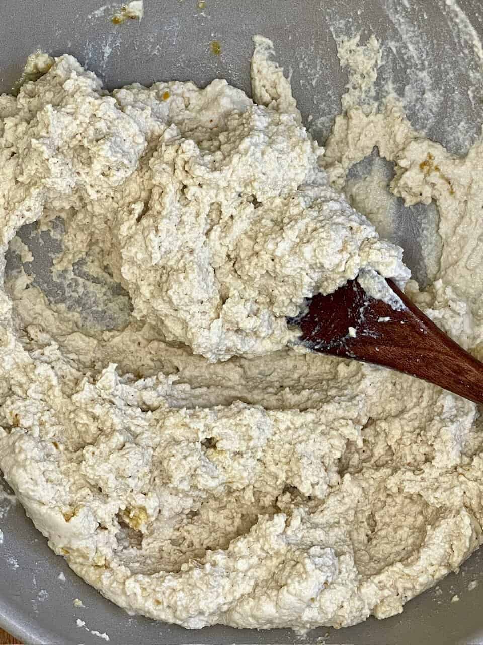 Buttermilk, crumbled cheese, or homemade ricotta cheese mixture in a mixing bowl, with a wooden spoon.