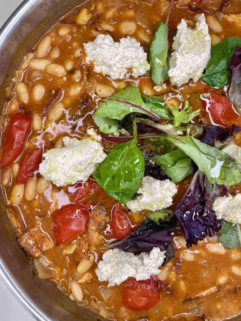 Savory bean and vegetable soup with fresh greens and cheese, healthy plant-based recipe, vegan dinner option.